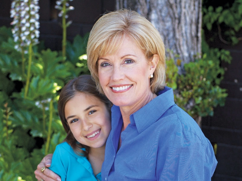 Grandmother and granddaughter sitting outside smiling.